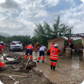 Voluntarios de Cruz Roja quitando barro