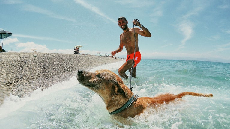 Hombre en la playa disfrutando con su perro