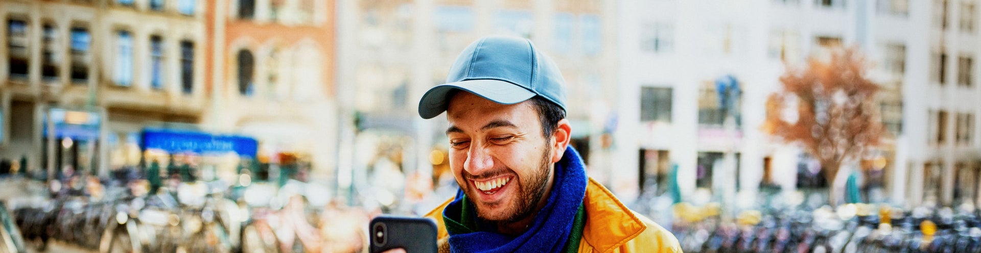 Hombre con gorra riendo mientras mira el móvil