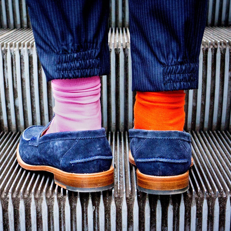 Zapatos con calcetines de colores subiendo escaleras mecánicas