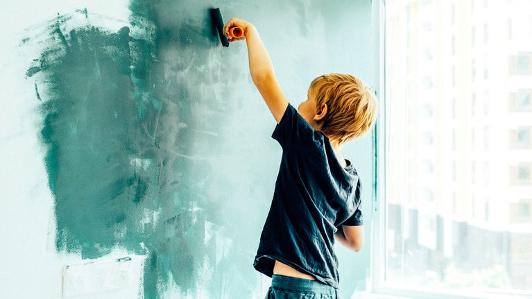 niño pintando la pared de verde