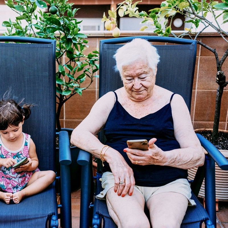 abuela y nieta en tumbonas mirando el móvil