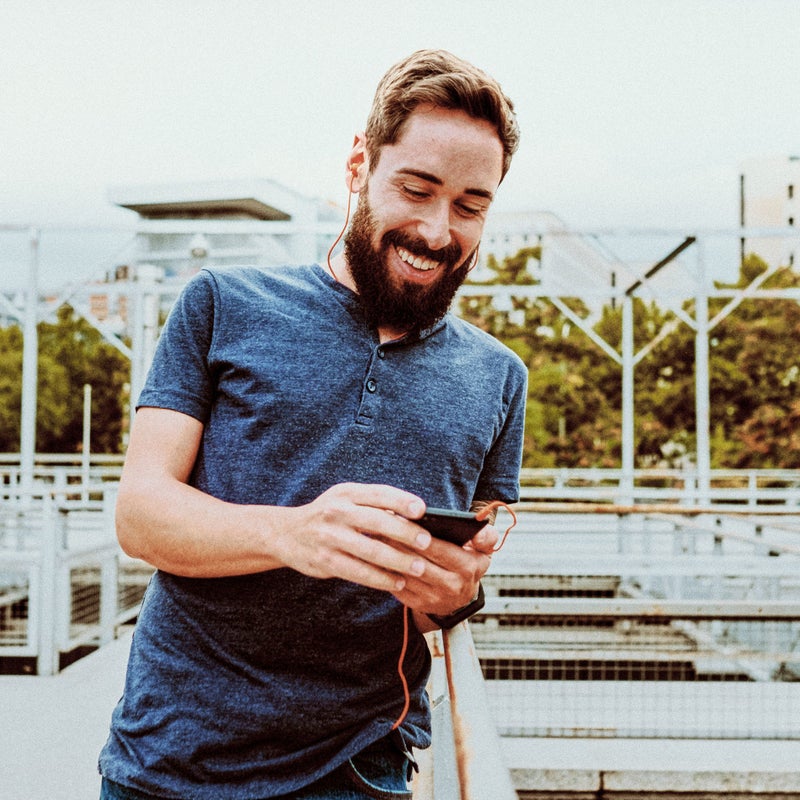 Hombre sonriente con camiseta azul mirando el movil