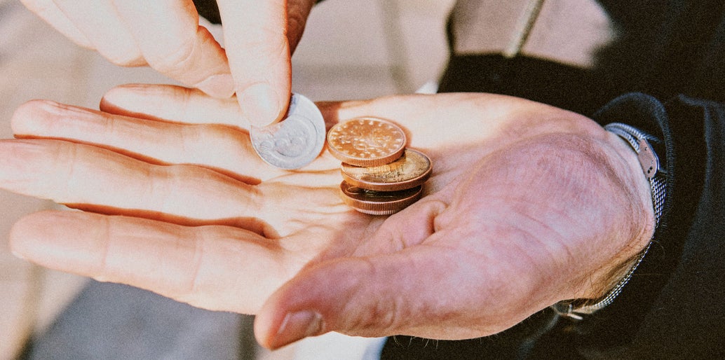 Mano de una persona sosteniendo monedas de diferentes valores