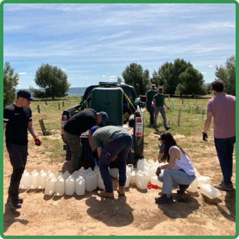 Grupo de personas cogiendo botellas de agua para las plantas