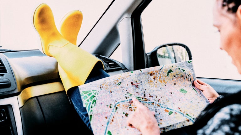 Mujer mirando un mapa en el coche con botas de agua amarillas