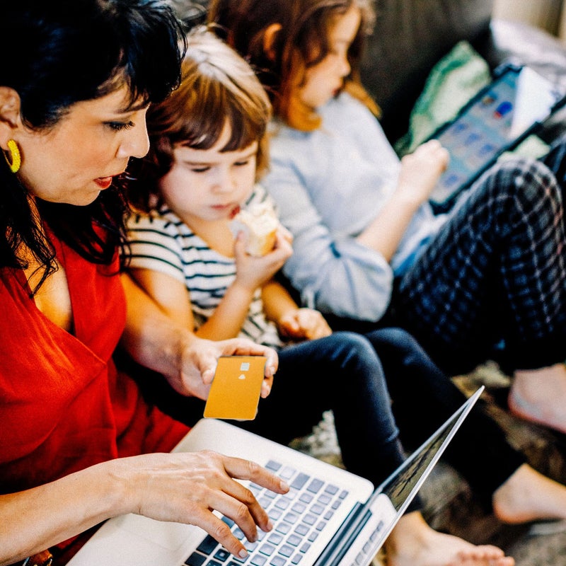 Mujer sonriendo mientras paga con tarjeta online con hijo