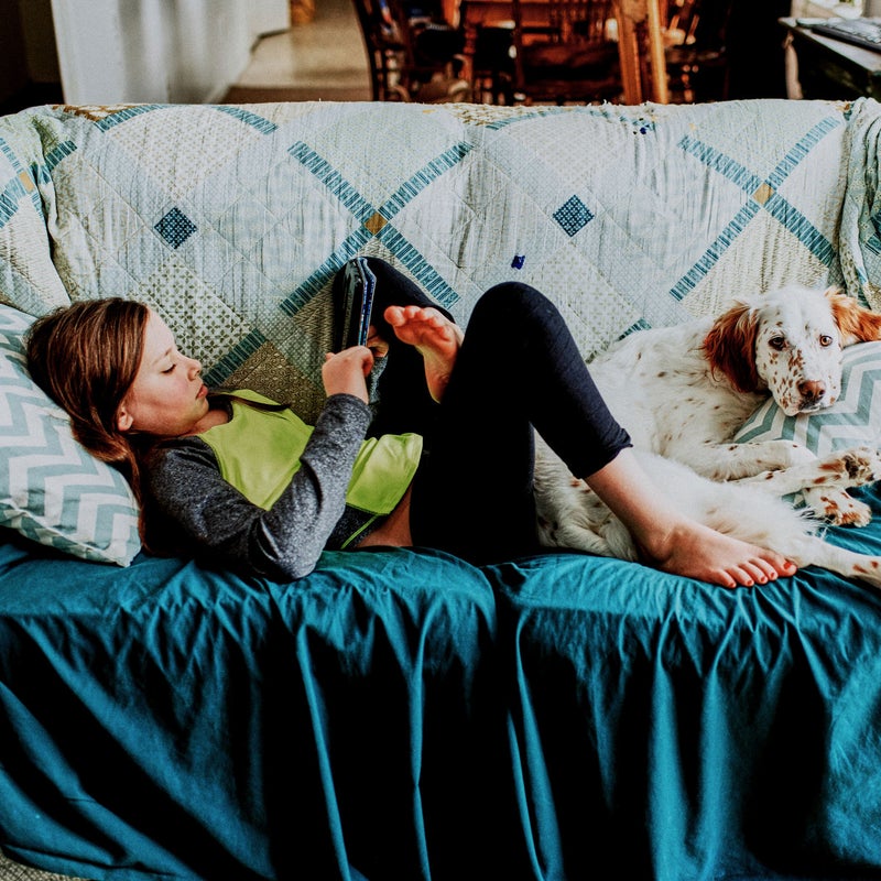 niña en el sofa con su perro mirando el móvil