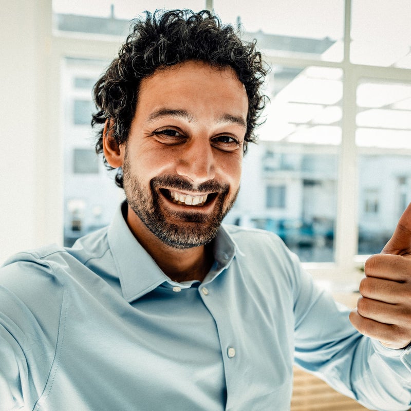 Hombre sonriente con camisa celeste en oficina