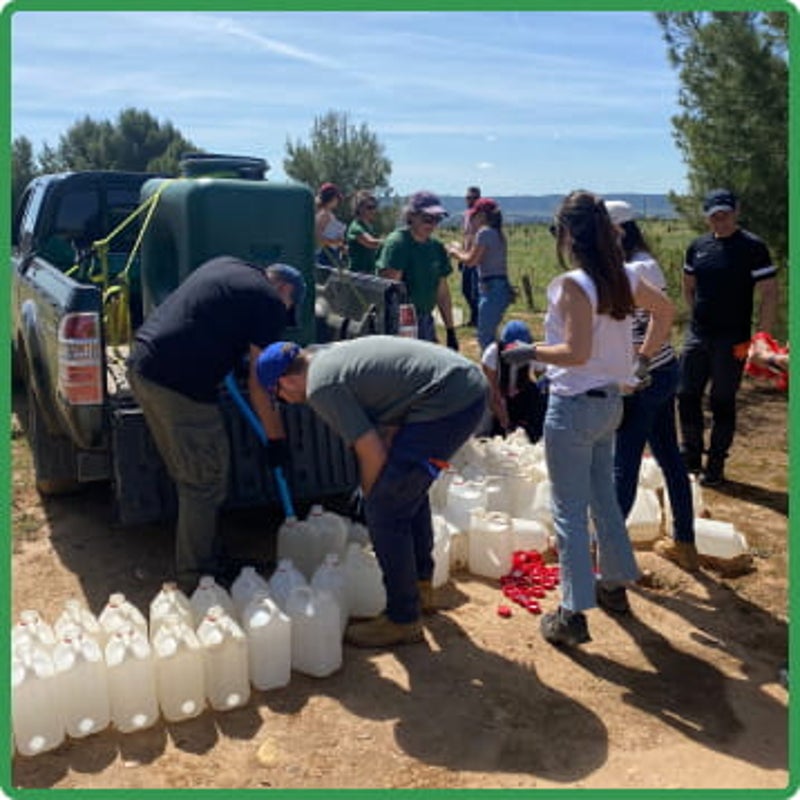 Personas llenando botellas con agua en el campo
