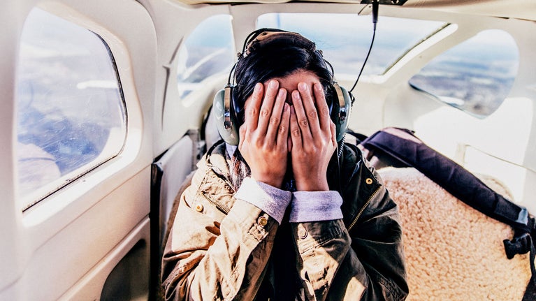 Mujer tapándose los ojos en un avion