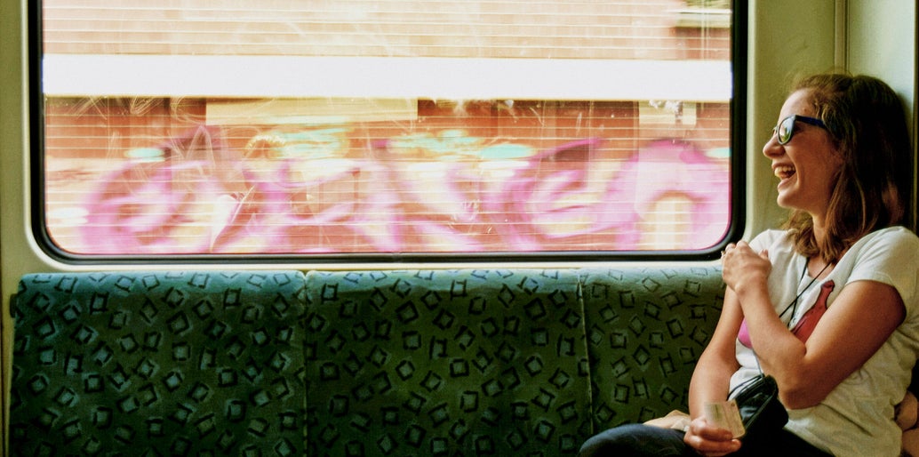 Mujer riendo y mirando por la ventana de un tren