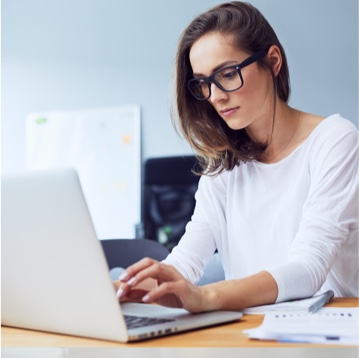Chica con gafas trabajando en l aoficina mirando el ordenador portátil