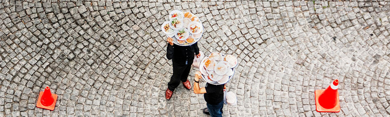 dos camareros cargados con bandejas de comida y bebida