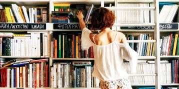 Chica mirando una estantería con libros